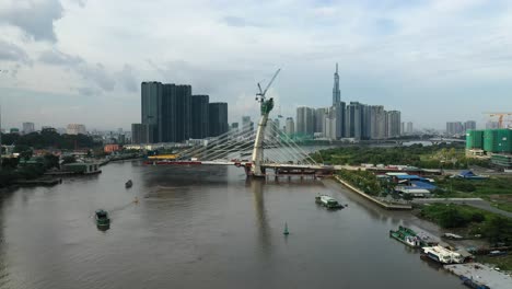 Vuelo-Aéreo-Hacia-El-Puente-Thu-Thiem-Dos-En-Construcción-Con-Edificios-Clave-Del-Horizonte-De-La-Ciudad-De-Saigón,-Incluidos-Vinhomes-Golden-River-Y-Punto-De-Referencia