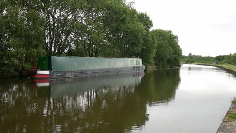 British-long-canal-narrow-boat-moored-along-scenic-English-boating-marine-countryside-waterway