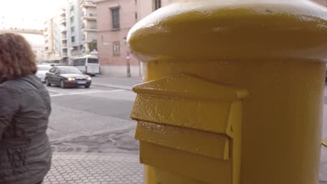 La-Gente-Camina-Por-El-Buzón-Amarillo-En-Sevilla,-España,-Primer-Plano-En-El-Buzón