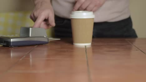 Hand-paying-by-card-with-take-out-coffee-cup-wide-shot