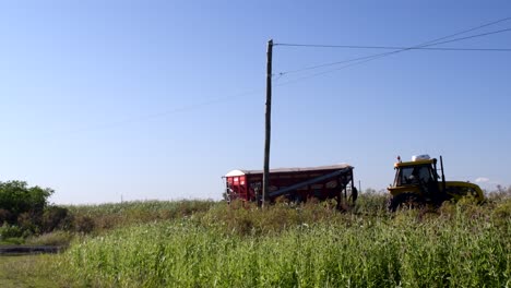 Vista-De-Un-Tractor-Que-Lleva-Un-Remolque-De-Cosecha-A-Través-De-Un-Camino-Rural-En-Santa-Fe,-Argentina