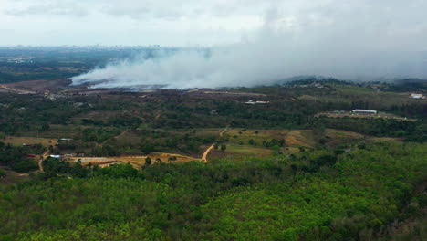 Aerial,-drone-shot,-towards-a-Grass-fire-burning,-a-huge-toxic-smoke-cloud-causing-global-warming-and-climate-change,-cloudy-day,-in-South-Africa