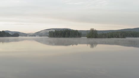 Foggy-Glass-like-reflective-water-on-Prong-Pond-low-angle-aerial