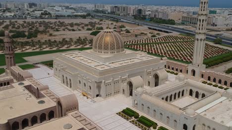 Vista-Aérea-De-Drones-De-La-Increíble-Gran-Mezquita-Del-Sultán-Qaboos-Panorámica-De-Izquierda-A-Derecha-Mientras-Domina-La-Ciudad-De-Muscat-En-Muscat-En-Omán