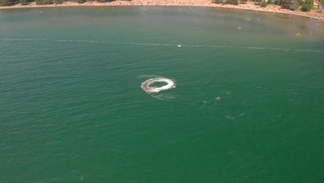 Drone-flying-over-man-on-jetski-in-green-water-sea