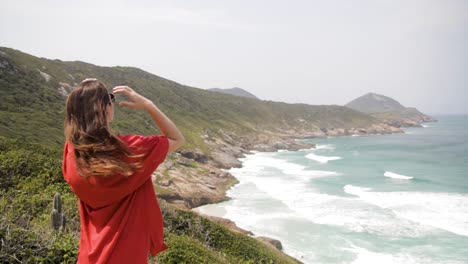 Young-woman-enjoying-the-sea-breeze-on-her-face-and-hair,-many-rocks-on-the-sea-slope-in-Praia-Brava,-Arraial-do-Cabo,-Rio-de-Janeiro,-Brazil