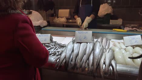 Meeresfrüchteverkäufer-In-Zeitlupe-Reinigt-Fisch-Auf-Dem-Markt,-Blick-Hinter-Den-Kunden