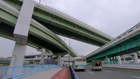 Panorama-shot-of-transport-driving-down-road-and-railway-in-Osaka,-Japan
