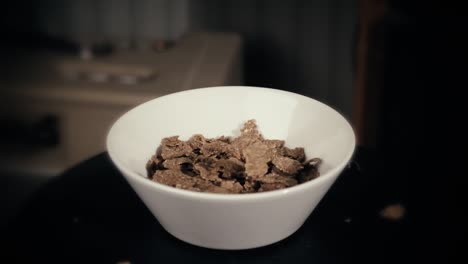 All-bran-cereal-being-poured-to-a-scandinavian-white-bowl-in-slow-motion