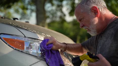 Profile-closeup-of-funny-man-washing-car-headlights-and-spraying-water-in-his-face-by-accident