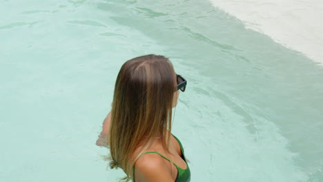 Close-shot-of-tanned-girl-in-bikini-floating-inside-the-pool