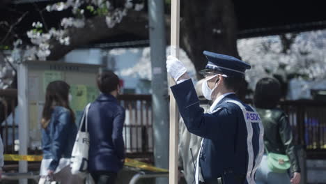 Policía-Japonés-Con-Mascarilla-Manteniendo-El-Orden-Durante-El-Hanami-En-La-Pandemia-En-Tokio,-Japón