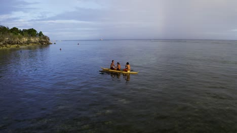 aerial-pan-shot-of-three-Philipino-boys-in-the-boat-swimming-in-the-sea-at-Panglao