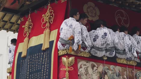 Japanese-People-Wearing-Kimonos-Sitting-On-The-Giant-Float-Moving-Forward-During-The-Yamaboko-Junko-Procession-Of-Floats,-Gion-Matsuri-Parade---close-up-slowmo