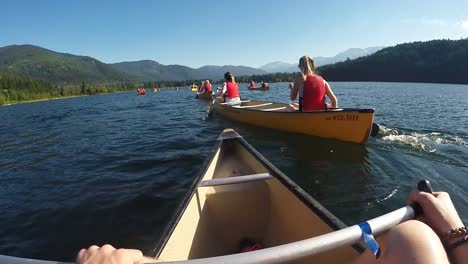 POV-action-camera-wide-shot-as-people-canoeing,-taking-over-on-a-lake-bright-sunny-day