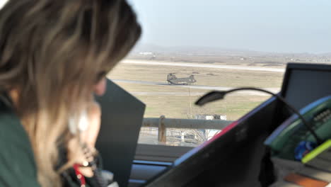 View-of-a-Chinook-helicopter-as-seen-from-the-ATC-tower-with-a-Caucasian-female-operator-talking-on-the-phone-in-the-foreground