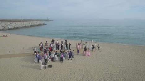 Audience-Taking-Photo-of-Couple-at-Beach-Wedding,-Aerial-Circling