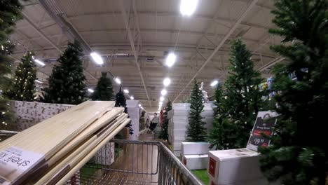 Retail-shopping-cart-moving-down-indoor-Christmas-tree-aisle-in-shopping-mall-during-covid-pandemic