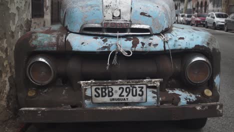 Close-up-of-front-of-rusty-old-Ford-model-parked-on-street