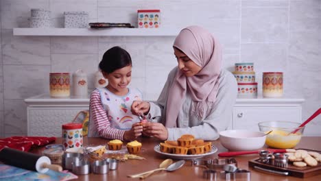 Muslimische-Mutter-Mit-Ihrer-Schönen-Tochter,-Die-Gemeinsam-In-Der-Küche-Cupcakes-Backt