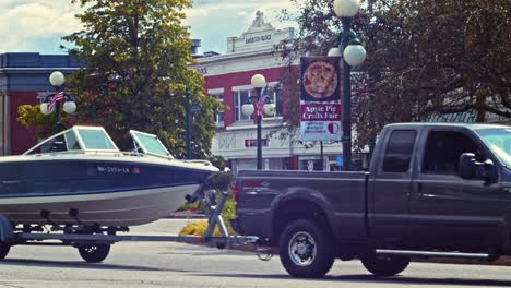 Boat-On-A-Trailer-Being-Towed-By-A-Black-SUV-On-The-Street---Newport,-New-Hampshire,-US---static-shot