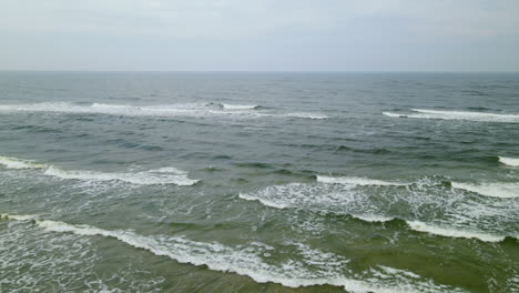 Scenic-View-Of-Ocean-Sea-Waves-Splashing-On-Sandy-Coastline-With-Tourist-Sightseeing-In-Wladyslawowo,-Poland