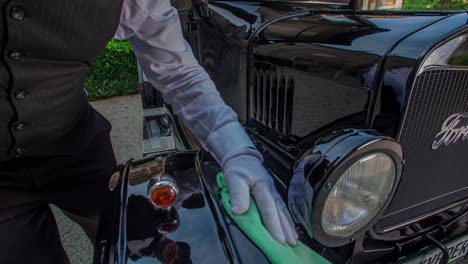 Formal-suited-man-with-top-hat-waves-goodbye-and-wipes-a-vintage-ford-car