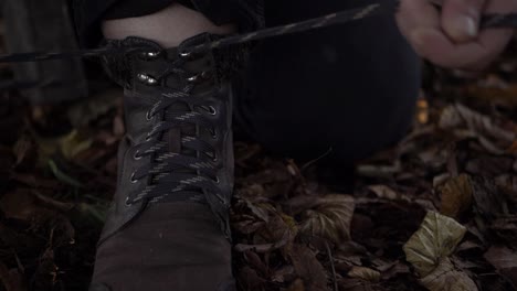 Hiker-tying-boot-laces-in-autumn-leaves-close-up-shot