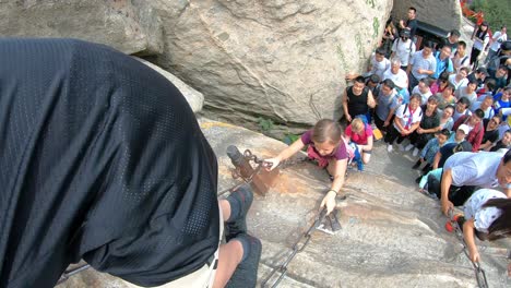 Tourists-climbing-up-the-vertical,-steep,-cut-into-rocky-edge-stairs-on-a-mountain-trail-to-the-North-and-West-Peak-on-Huashan-mountain,-Xian,-Shaanxi-Province