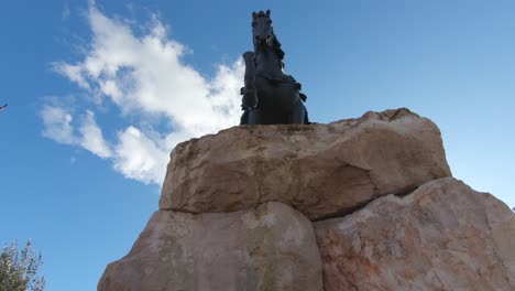 Statue-of-National-Albanian-hero-overlooking-the-vast-main-Skanderbeg-square-in-Tirana,-Albania---Wide-low-angle-orbit-shot