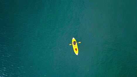 Aerial-top-down-shot-of-an-unrecognizable-man-rowing-against-current-at-the-sea