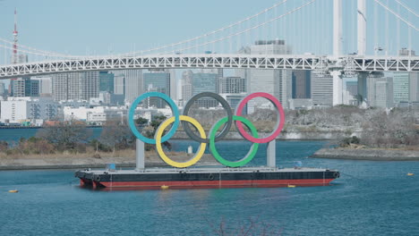 Denkmalausstellung-Der-Olympischen-Ringe-In-Odaiba-Mit-Einem-Panorama-Der-Regenbogenbrücke-über-Die-Bucht-Von-Tokio-In-Minato,-Tokio,-Japan