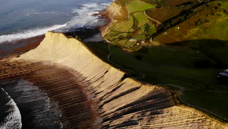 4K-drone-aerial-shot-of-a-cliff-and-waves-in-the-coastline-sea-in-Zumaia,-Spain