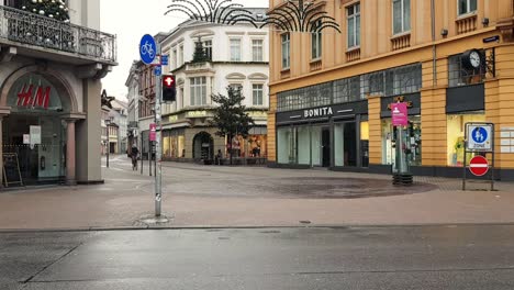 Waiting-at-traffic-light-then-crossing-road-to-empty-city-during-corona-lockdown,-Heidelberg-Germany