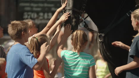 Young-boys-and-girls-petting-horse-during-small-town-parade,-Slow-Motion