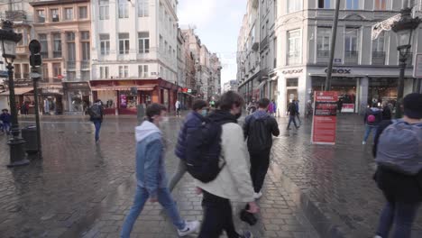 Slow-steady-pov-shot-of-pedestrians-with-mask-walking-on-grasmarkt-street-in-Brussels-during-sunny-day