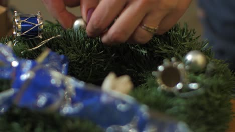 Woman-making-a-fir-Advent-wreath-for-Christmas-Eve-and-placing-decorations,-diy-craft-decoration,-winter-traditions,-seasonal-holidays,-hands-close-up-shot