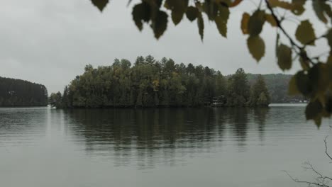 Herrlicher-Blick-Auf-Den-Lac-Viceroy-Lake-In-Montpellier,-Quebec-Mit-Baumblättern-Im-Vordergrund-Und-Einer-Insel-In-Der-Ferne