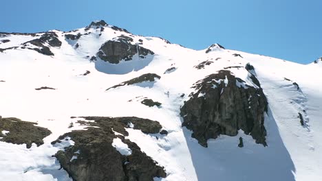 Bajada-Aérea-De-Un-Deportista-Muy-Hábil-Esquiando-Por-Una-Pendiente-Empinada-Cubierta-De-Nieve-En-El-Cerro-Piltriquitron,-El-Bolsón,-Patagonia-Argentina