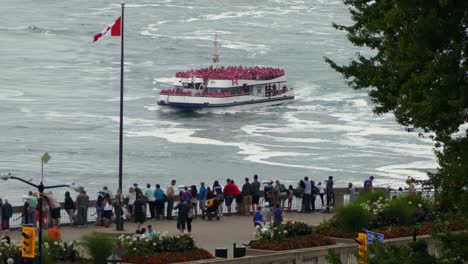 Turistas-En-Impermeables-Montando-Un-Barco-De-Crucero-En-El-Río-Niagara-Con-Espectadores-Mirando