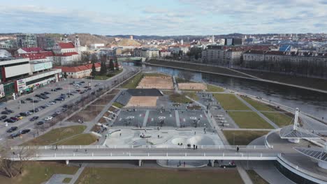 Luftaufnahme:-Skatepark-Und-Basketballfeld-Mit-Vielen-Menschen-In-Vilnius-Mit-Stadtpanorama