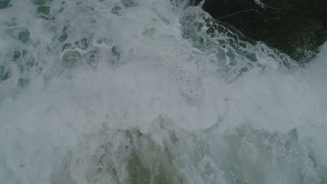 Rock-coast-shore-with-very-strong-waves-and-rough-sea-aerial-view-closeup-of-waves-hitting-rocks
