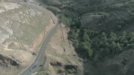 Aerial-forward-tilt-up-over-empty-road-crossing-Serra-de-Dentro-valley-on-Porto-Santo-island