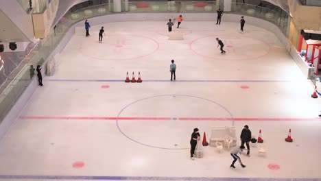 Se-Ve-A-Personas-De-Todas-Las-Edades-Disfrutando-Y-Aprendiendo-Patinaje-Sobre-Hielo-Bajo-Techo-En-Un-Centro-Comercial-En-Hong-Kong