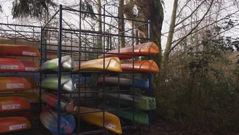 colorful-orange-red-blue-and-green-Canoes-stored-stacked-organized-on-a-metal-rack-during-autumn-fall-off-season