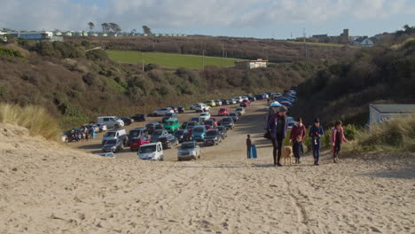 Family-arriving-at-parking-lot-at-crantock-beach,-wide-shot