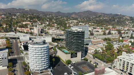 Aerial-view-of-the-Captal-records-building-and-the-101-freeway,-with-the-Hollywood-sign-in-the-background