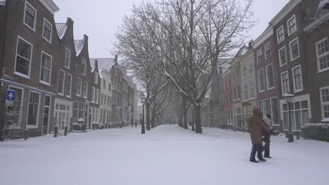 People-walking-through-snowy-Leiden-winter-streets,-Netherlands-old-city-in-snow