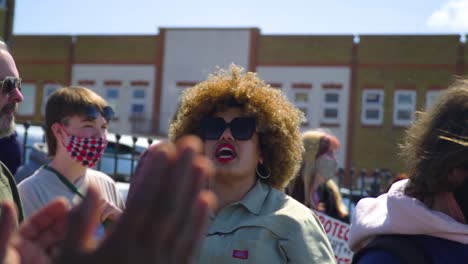 Adult-woman-with-afro-clapping-and-shouting-for-her-rights-with-a-friend-in-the-middle-of-the-protest-on-sunny-day