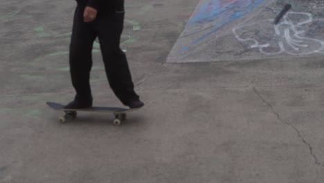 Slow-mo-medium-shot-of-skate-boarder-at-graffiti-covered-skate-park-in-Sheffield,-England-landing-trick
